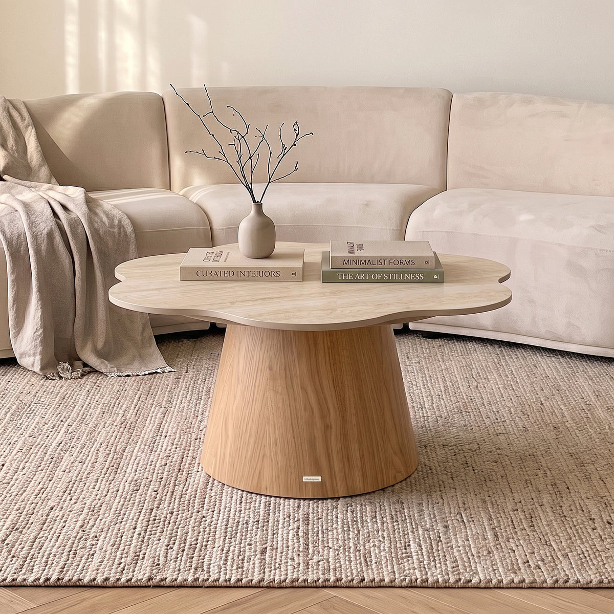 Modern round coffee table styled in a living room with sofa, rug, books, and vase