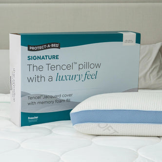 Protect-A-Bed Signature Tencel jacquard memory foam pillow, Soft, in its packaging box next to the pillow on a bed