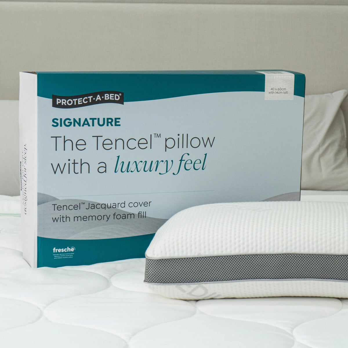 Protect-A-Bed Signature Tencel jacquard memory foam pillow, Medium, in its packaging box next to the pillow on a bed