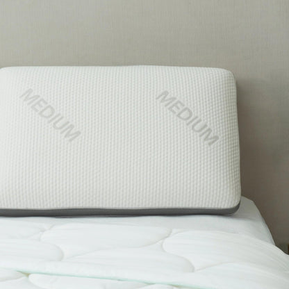 Signature memory foam pillow, Medium, with grey gusset trim, resting on a bed against a headboard