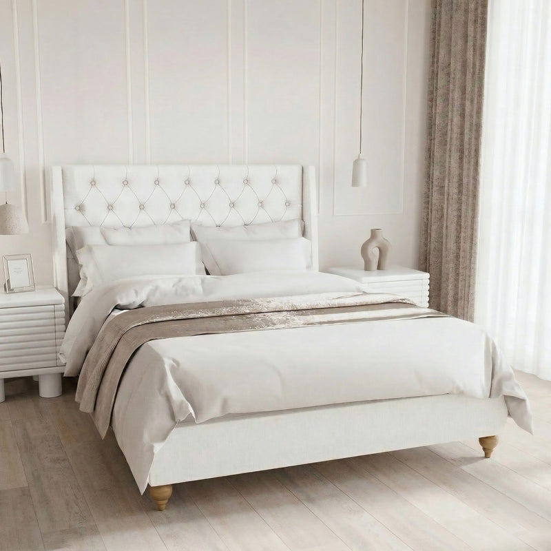 Elegant double bedroom with a white tufted wingback headboard, matching white nightstands, and soft neutral bedding for a bright, airy aesthetic.