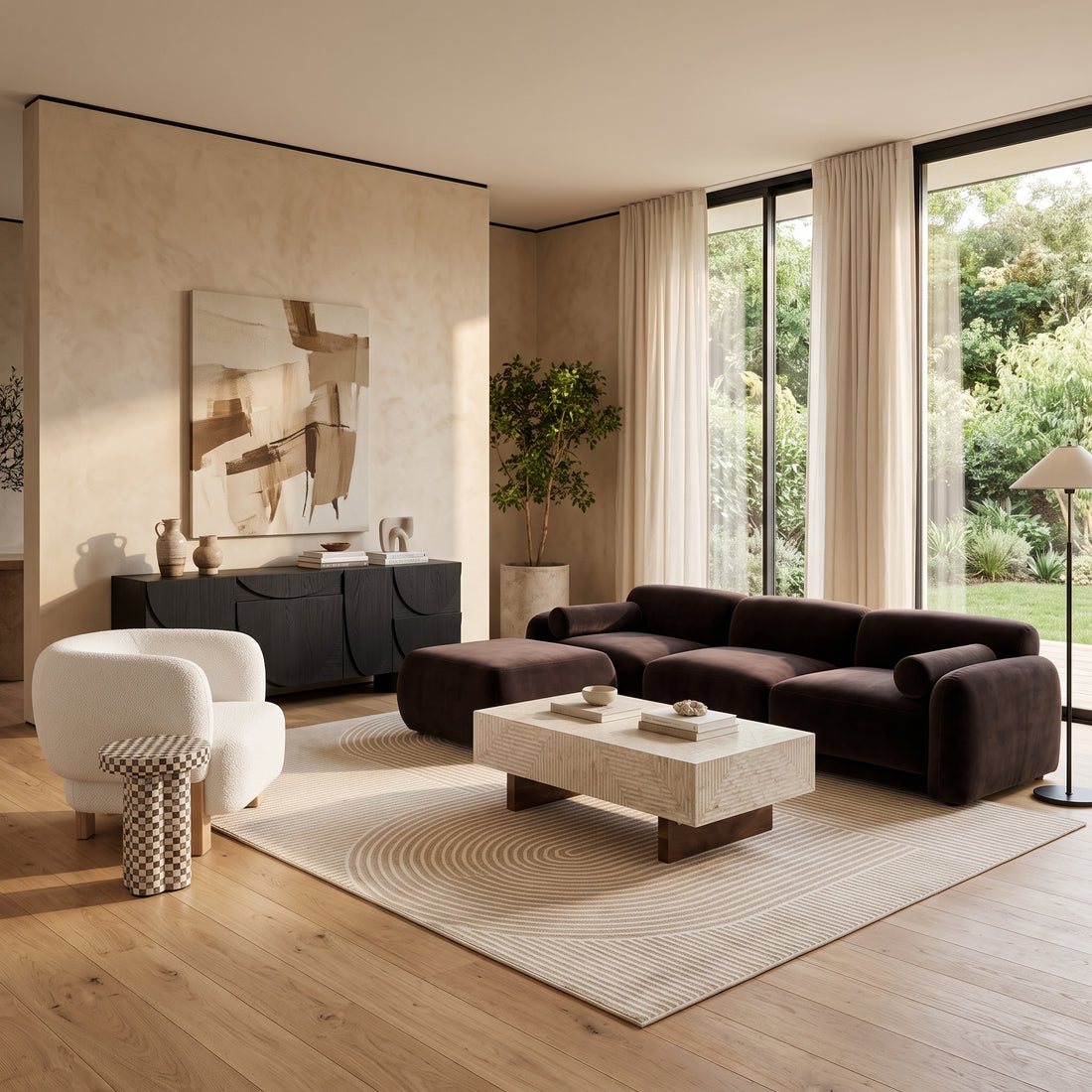 Dark brown velvet sofa with ottoman paired with a white bouclé armchair, travertine coffee table, and a black sideboard in a light-filled living room.