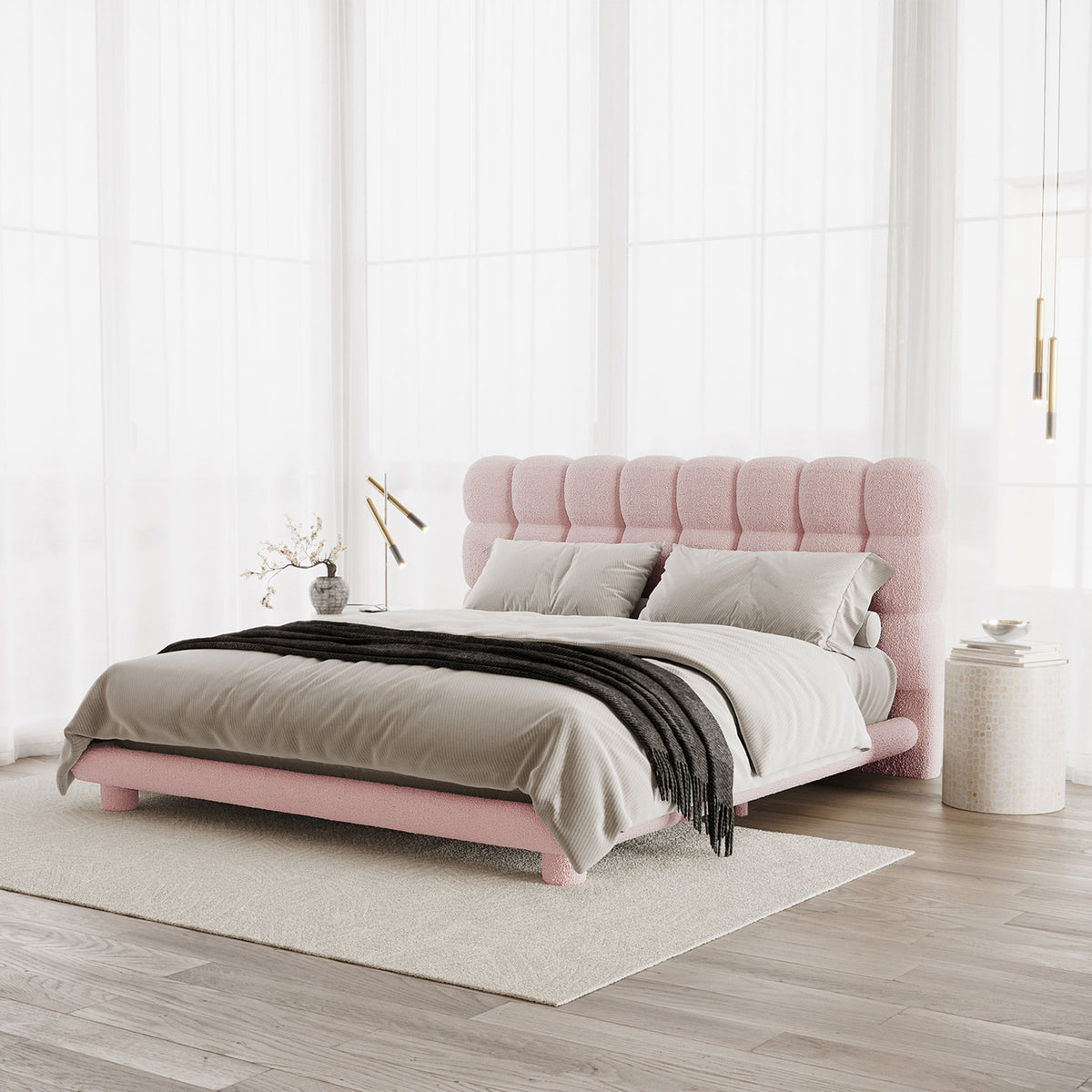 Pink boucle king bed frame with vertical channel tufting on headboard, shown with grey bedding and black throw in bright room