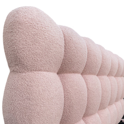 Close-up of pink boucle upholstered bed frame with curved, channel-tufted design