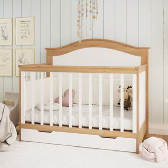 Azeem 3-in-1 Adjustable Solid Pine Baby Cot in Walnut Tone with white slats, arched headboard, storage drawer; adorned with star-patterned cushion, heart pillow, moose toy, and glittery mobile above.