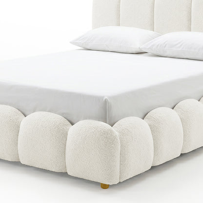 Close-up of the scalloped base and brass foot of the Brent King Gas Lift Bed in Boucle Cream White, showing white bedding