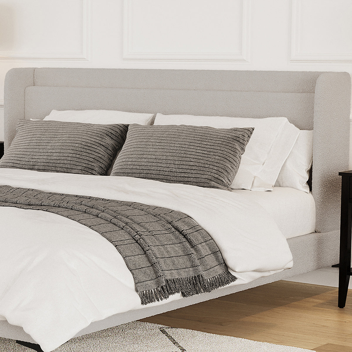 Beige boucle king bed frame with winged headboard, white bedding, grey cushions and throw blanket