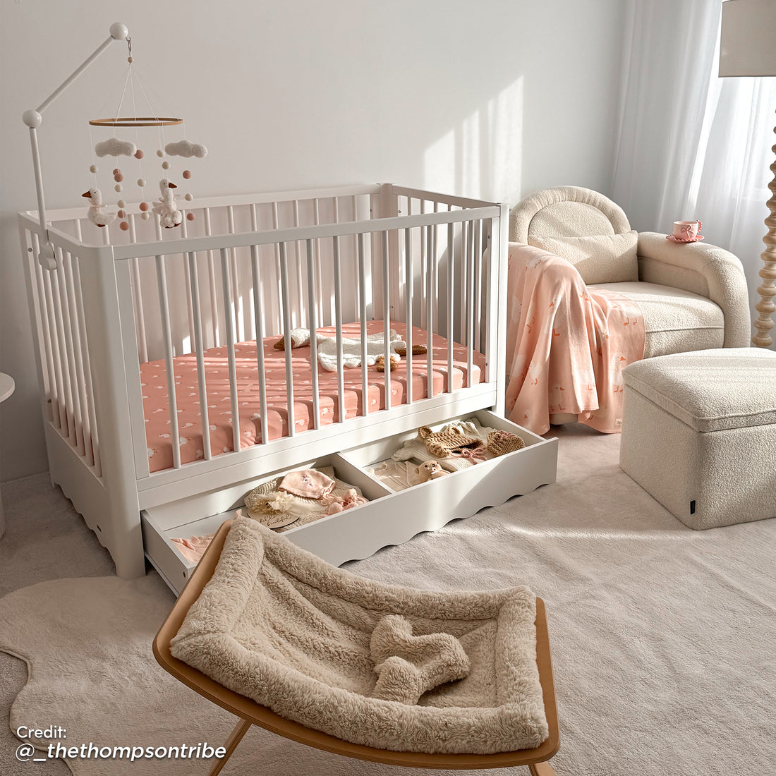 White timber baby cot with scalloped under-bed storage drawer, shown in nursery with pink bedding