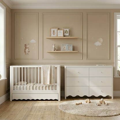 White timber baby cot with scalloped base and under-bed storage drawer, shown in nursery with matching chest of drawers