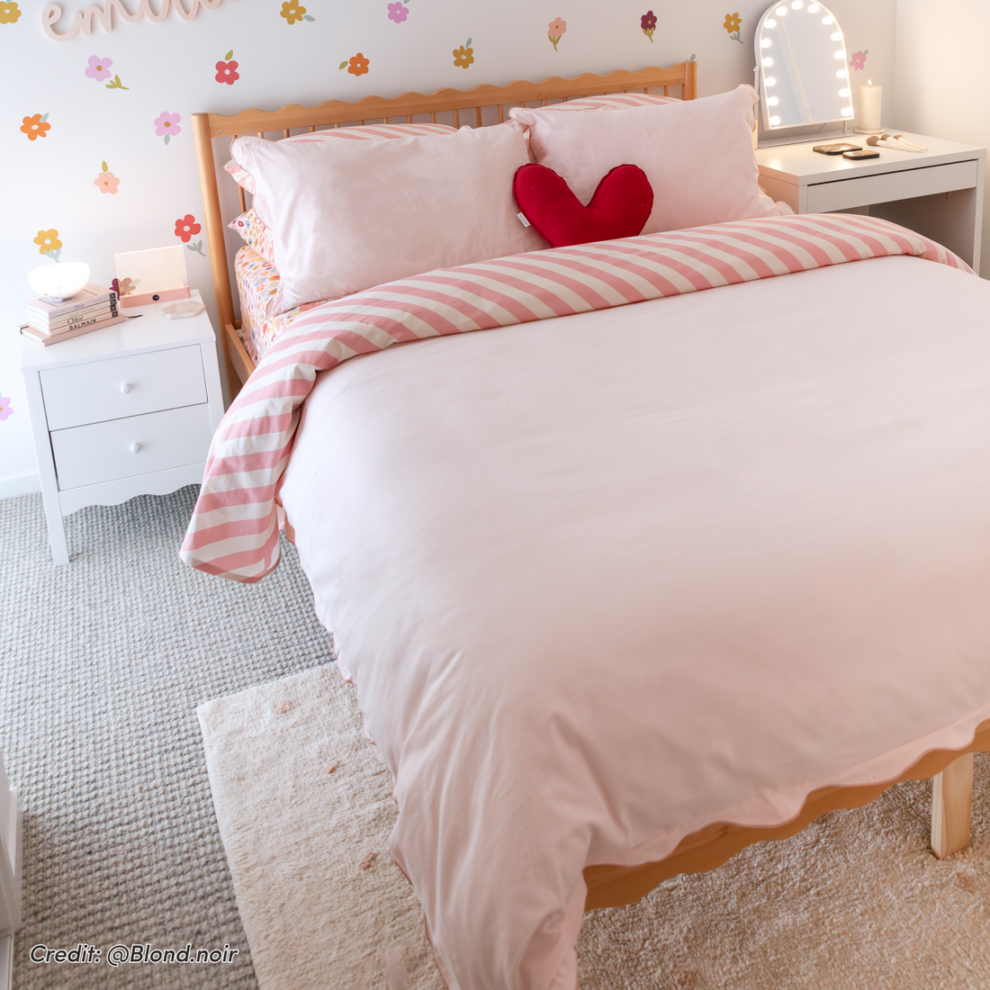 Natural hardwood scalloped double bed frame with pink and white striped bedding, red heart cushion, and curved headboard in a