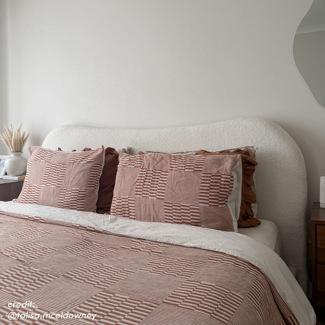 Ginnie Bouclé Curved King Bed Frame in Cream White with textured curved headboard, styled with rust and white geometric