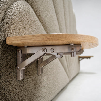 Close-up of scalloped boucle headboard with wooden shelf on brushed metal bracket