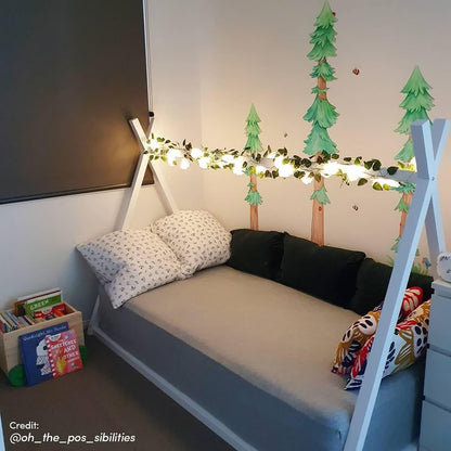 Helena Kids Single Solid Pine Teepee Bed Frame in White, styled with leaf garland lights, tree wall decals, black and white