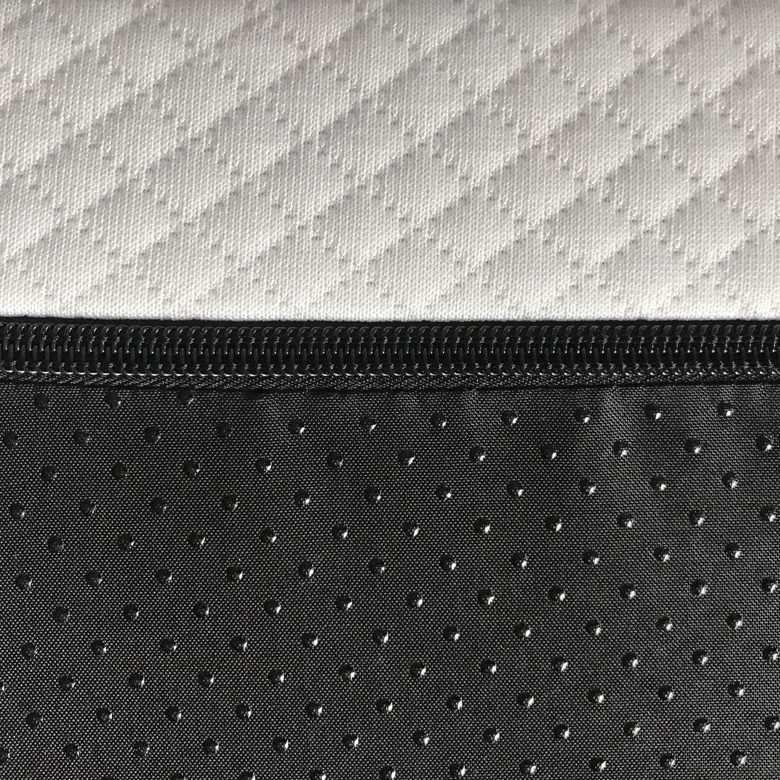 Close-up of white and black zippered mattress cover with geometric and dotted fabric patterns