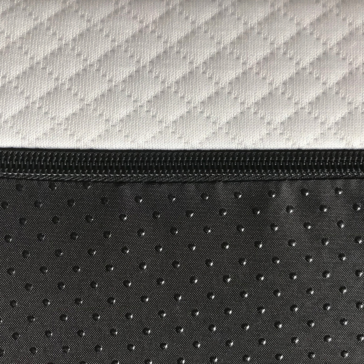 Close-up of white and black zippered mattress cover with geometric and dotted fabric patterns