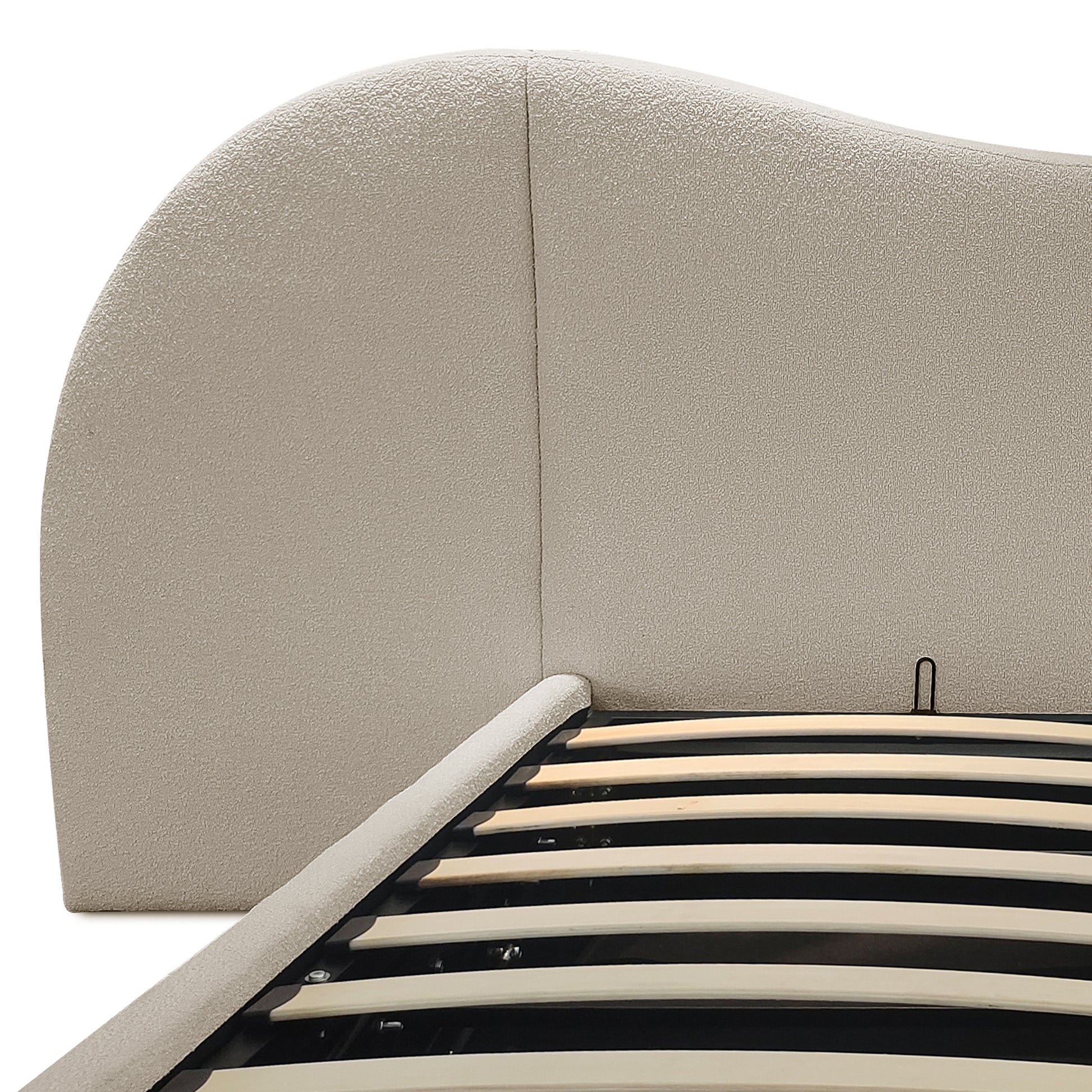 Close-up of beige boucle upholstered curved headboard and gas lift slatted base of king storage bed frame