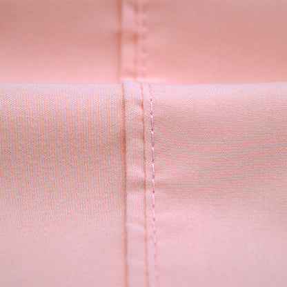 Close-up of blush pink bed sheet showing stitched seam and fabric texture