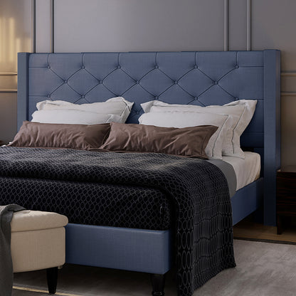 Maggie King Winged Fabric Bed Frame – Dark Blue featuring a tall, tufted headboard, crisp white pillows, brown accent pillows, and a dark patterned duvet, creating a sophisticated, contemporary bedroom ambiance.