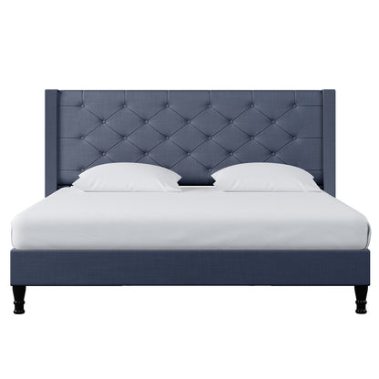 Maggie King Winged Fabric Bed Frame – Dark Blue with a tall, button-tufted headboard, white bedding, and dark wood legs, offering a blend of old-world charm and contemporary style.