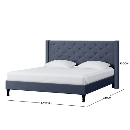 Maggie King Winged Fabric Bed Frame in Dark Blue, featuring a tufted headboard with studded details, visible dimensions, and luxurious upholstery, showcasing its grandeur and robust construction.