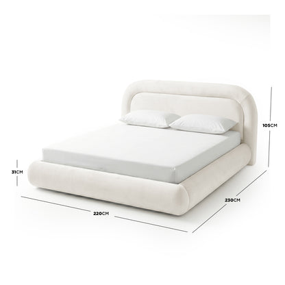 Upholstered king-size bed frame in cream white with curved headboard and footboard, shown with mattress and pillows on white