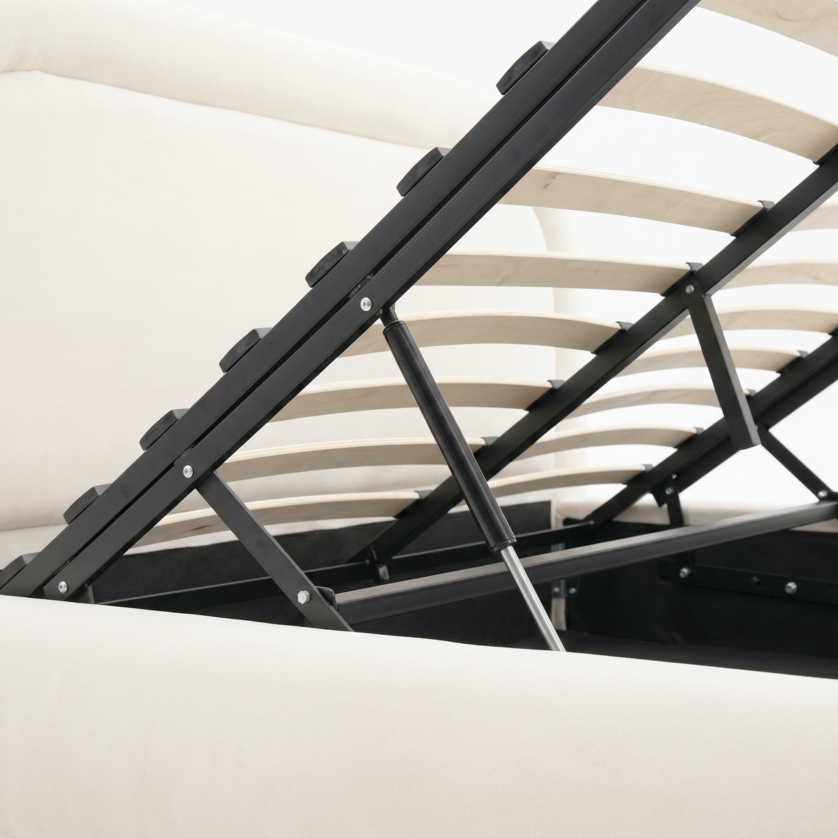 Cream white upholstered gas lift storage bed frame with black metal mechanism and wooden slats, shown in lifted position