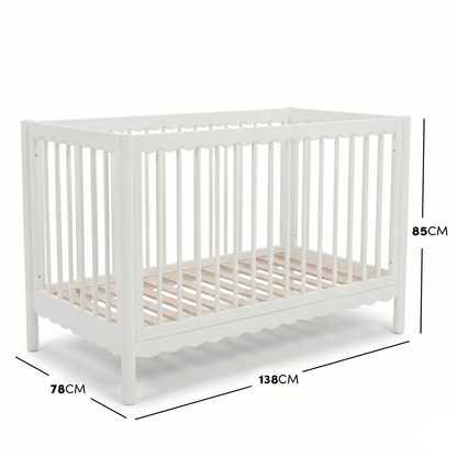 White timber baby cot with scalloped base molding and dimensions diagram.