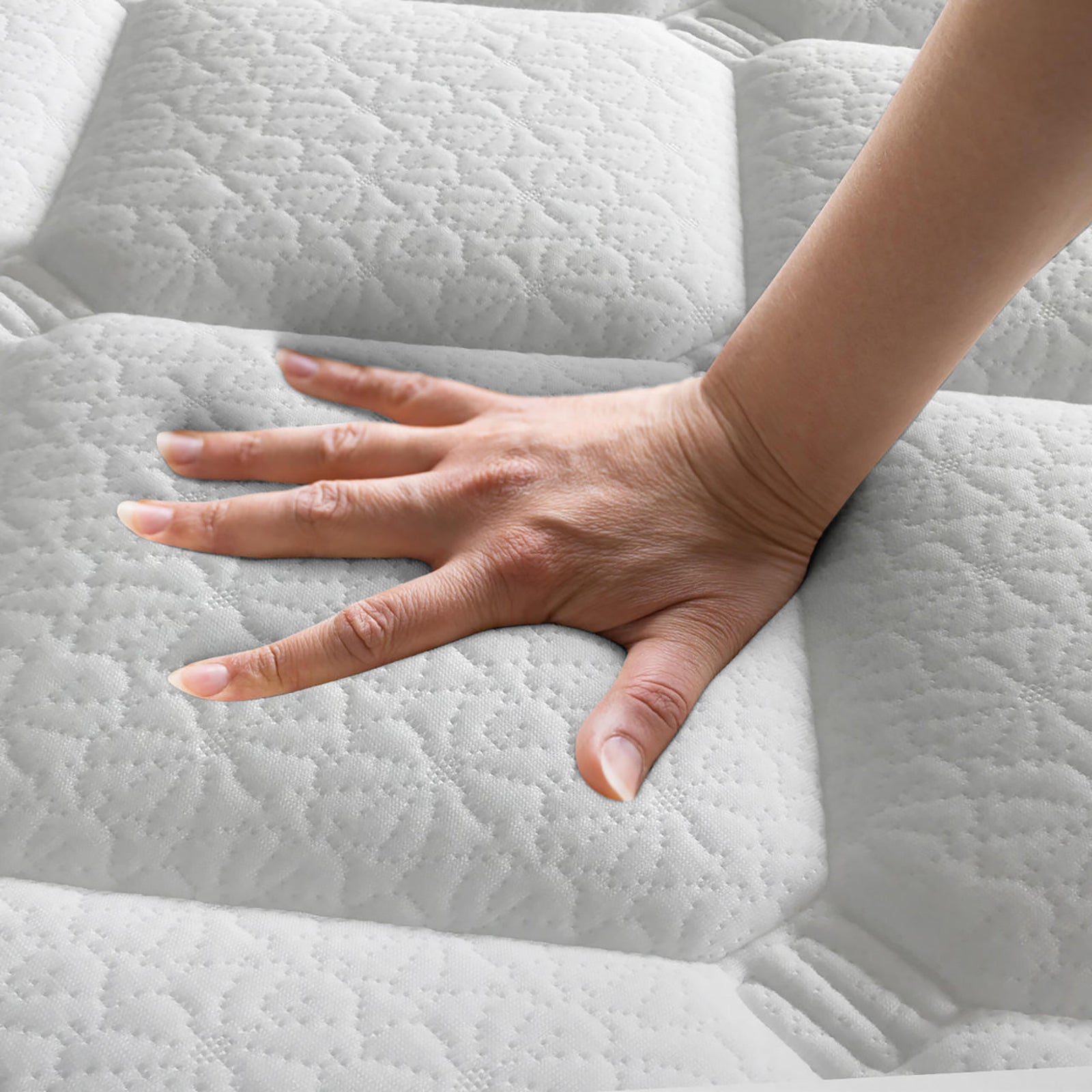 Hand pressing into white quilted pillow top mattress surface showing texture and softness