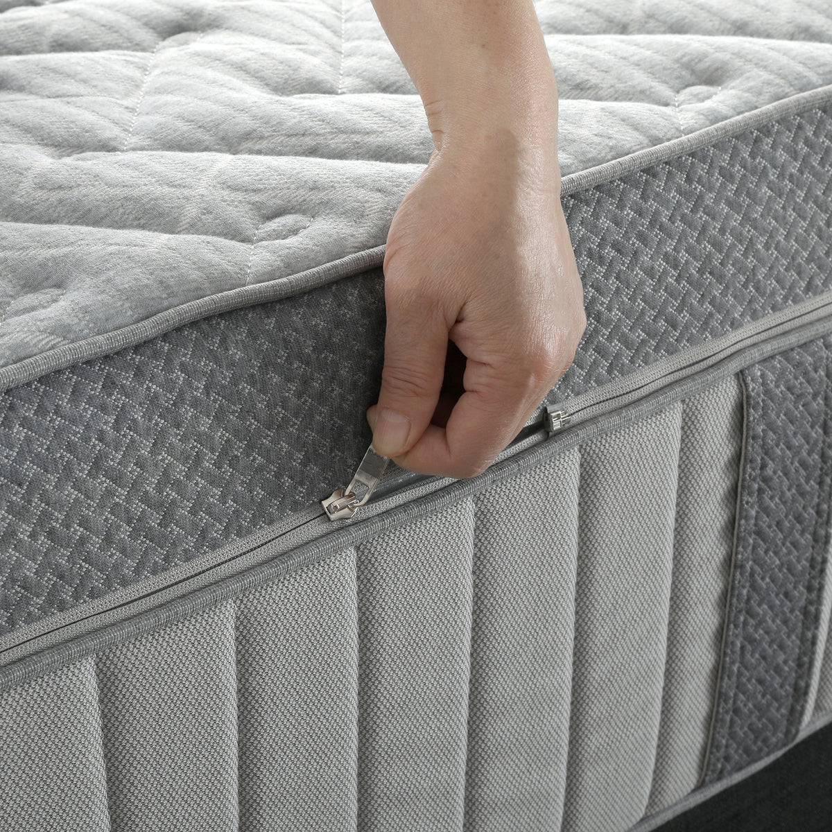 Close-up of a grey quilted mattress featuring a zip-off removable cover.