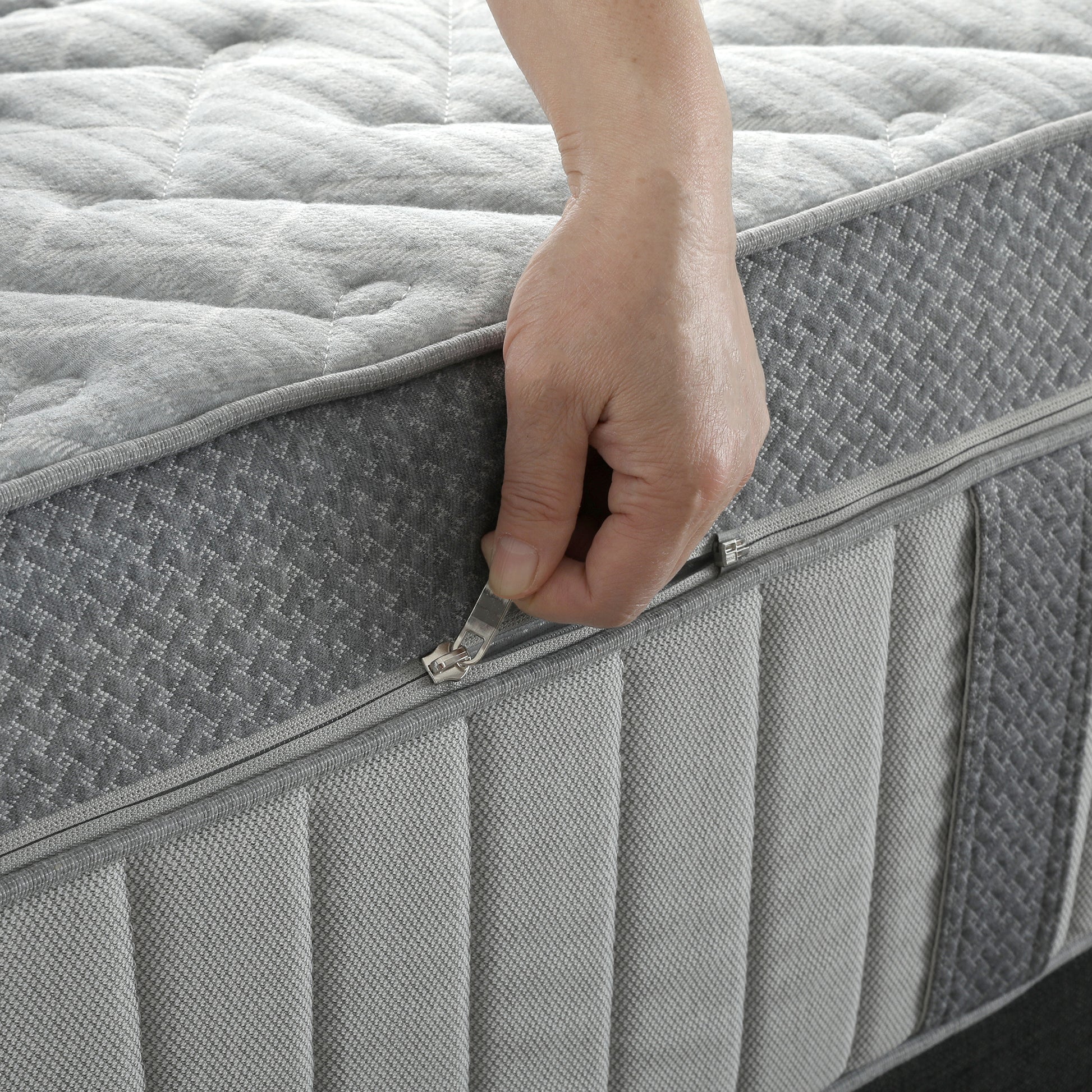 Close-up of a grey quilted mattress featuring a zip-off removable cover.