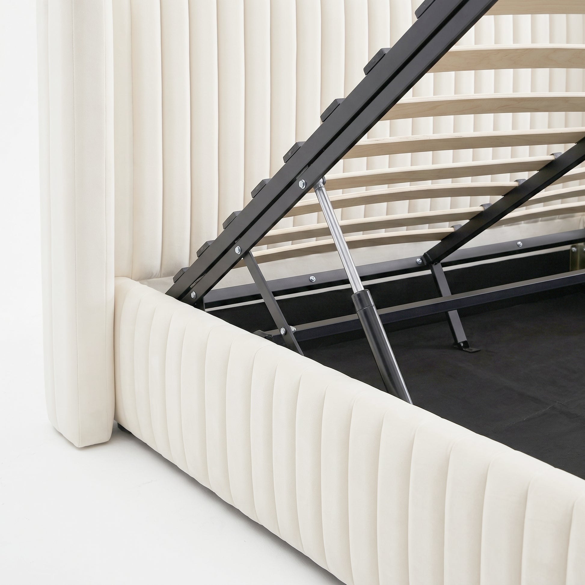 Close-up of gas lift mechanism on cream white velvet upholstered storage bed frame with wooden slats