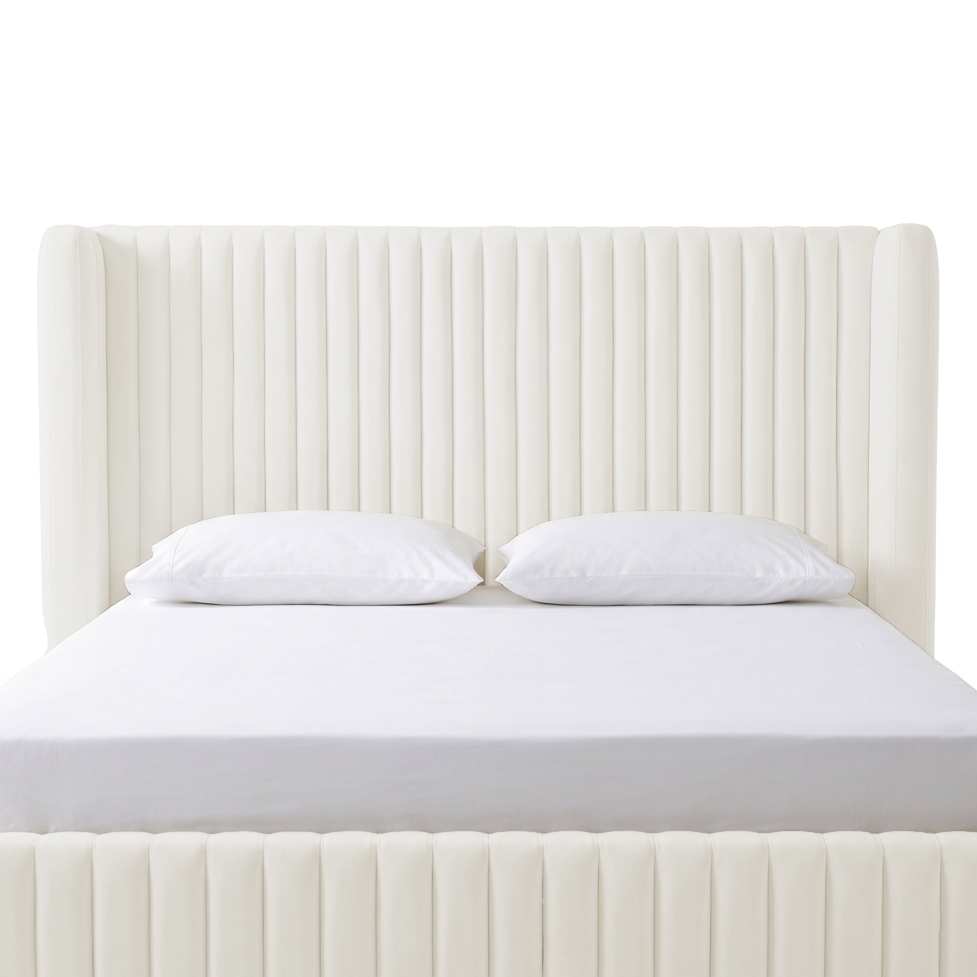 Cream white velvet upholstered bed with vertical channel tufting, white fitted sheet and two pillows