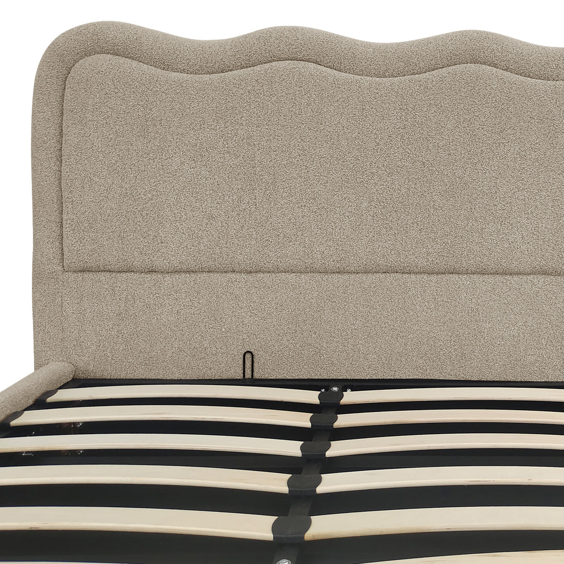 Close-up of beige boucle upholstered headboard and gas lift storage bed frame slats