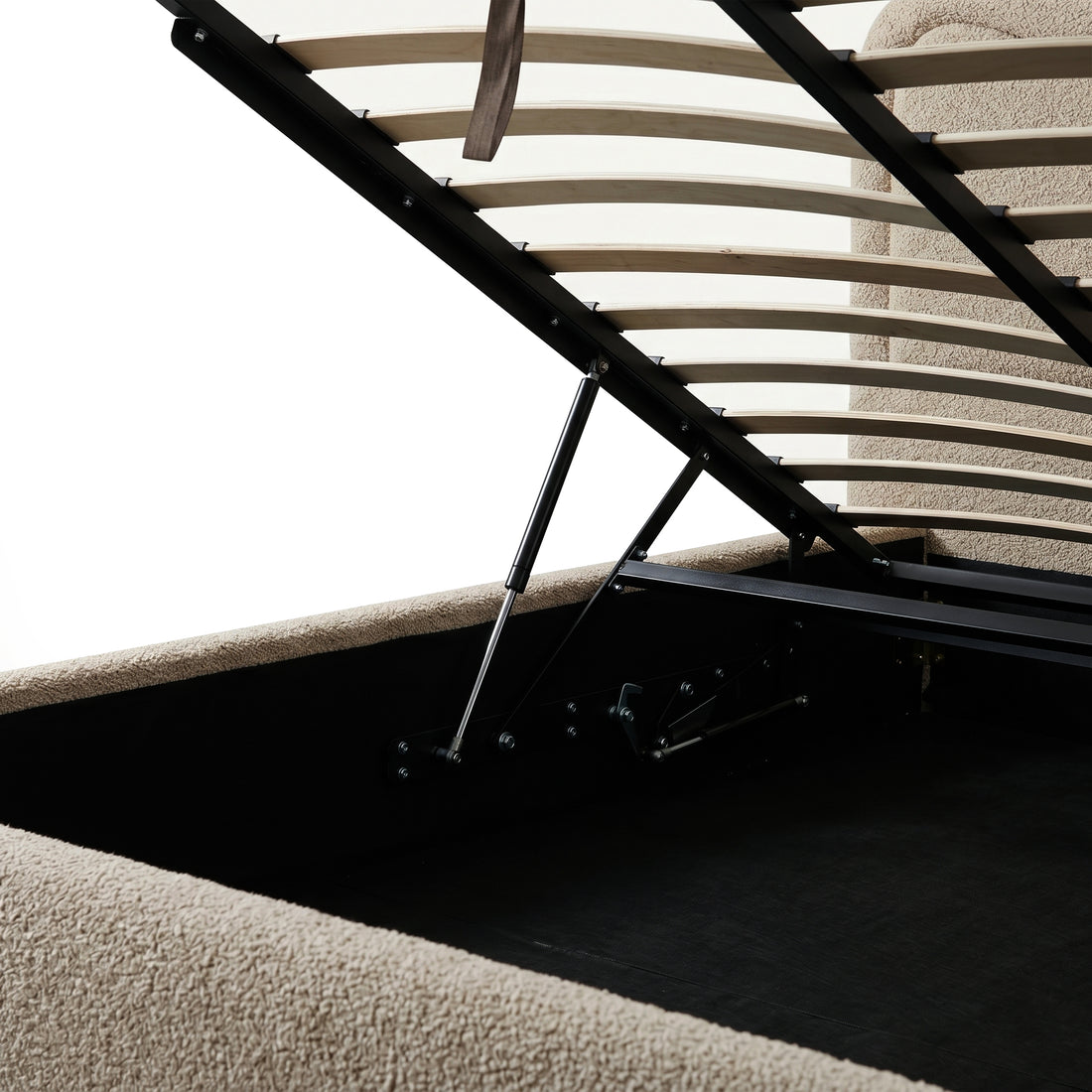 Beige boucle upholstered queen bed with gas lift storage mechanism, wooden slats and black metal frame visible