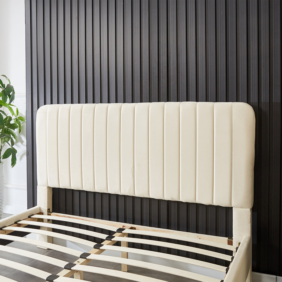 Seneca Queen Curved Velvet Fabric Bed Frame in Sandy White, featuring a tall cream upholstered headboard with vertical channeling, partly-assembled with curved wooden slats for mattress support.