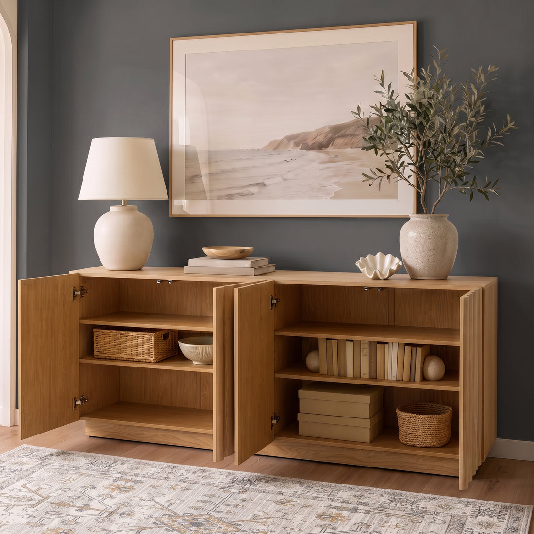 Oak sideboard with open fluted doors revealing styled interior shelves, books, and storage baskets against a dark grey accent wall.