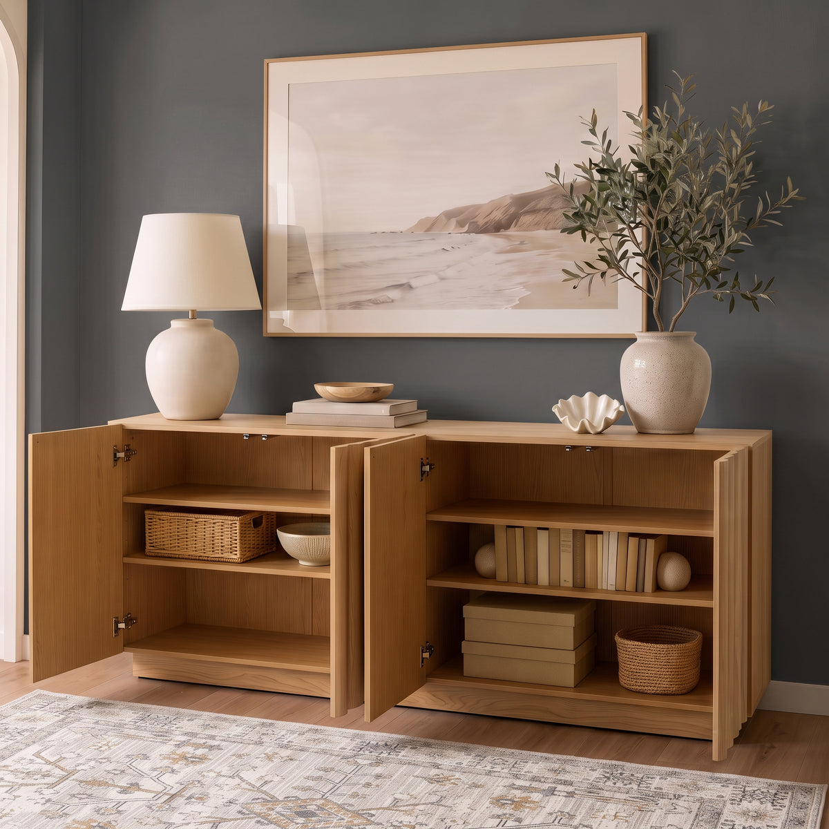 Oak sideboard with open fluted doors revealing styled interior shelves, books, and storage baskets against a dark grey accent wall.