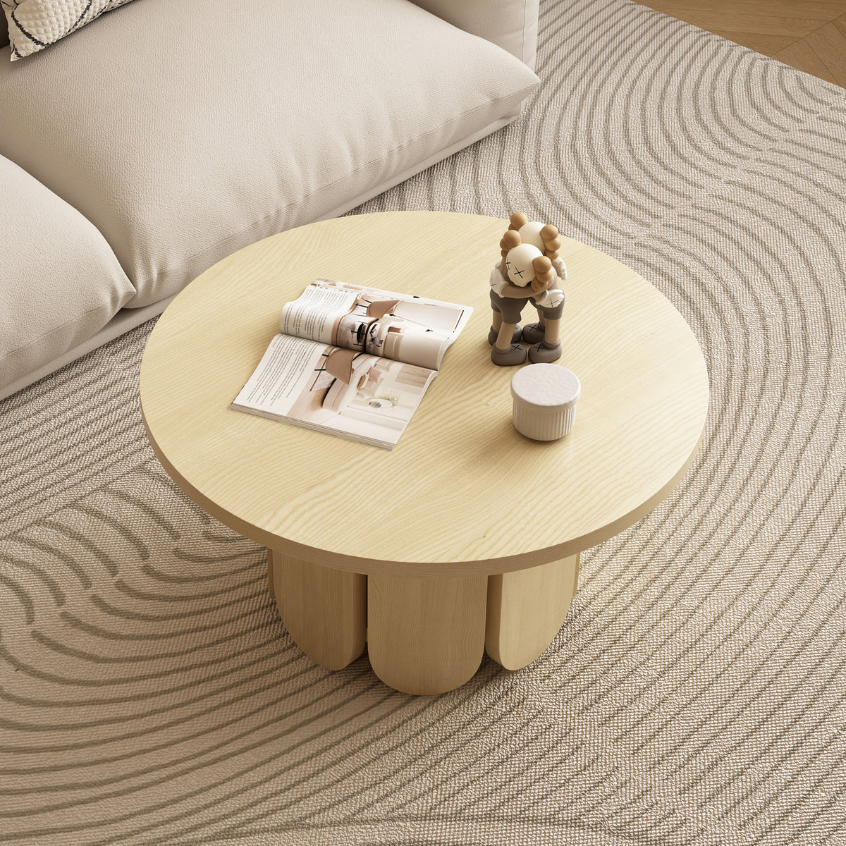 Hugo 70cm round coffee table in natural ash wood with three curved legs, styled with magazine, figurine and small white