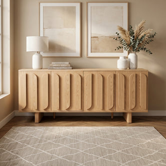 Wooden sideboard styled in a modern living space with books, lamp, vase, and wall art