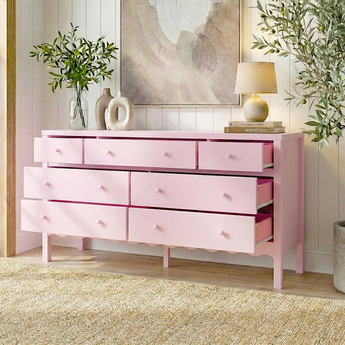 Pink Serra 150cm solid pine 7-drawer lowboy dresser with scalloped base, styled in a room with lamp, vases, plants and wall