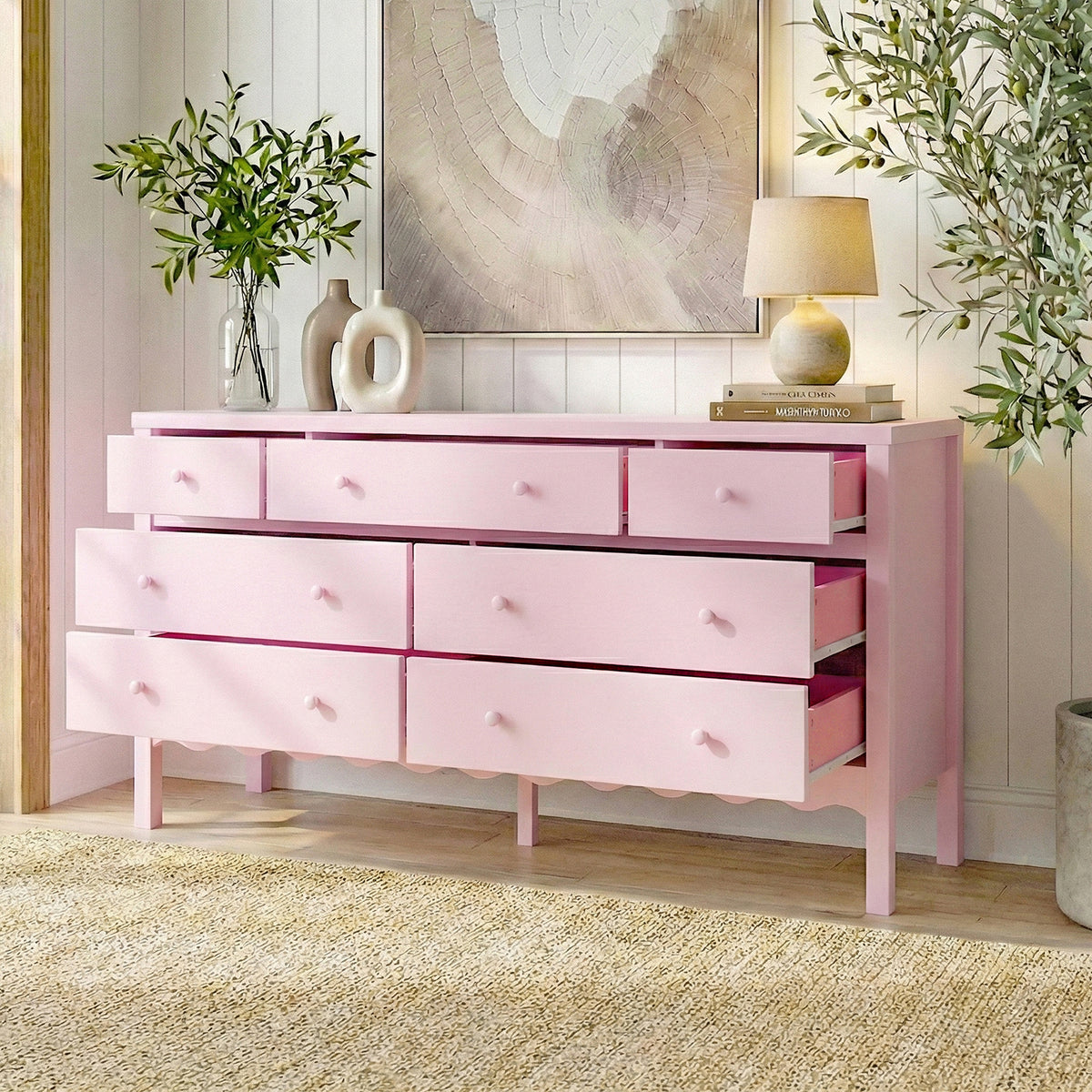 Pink Serra 150cm solid pine 7-drawer lowboy dresser with scalloped base, styled in a room with lamp, vases, plants and wall