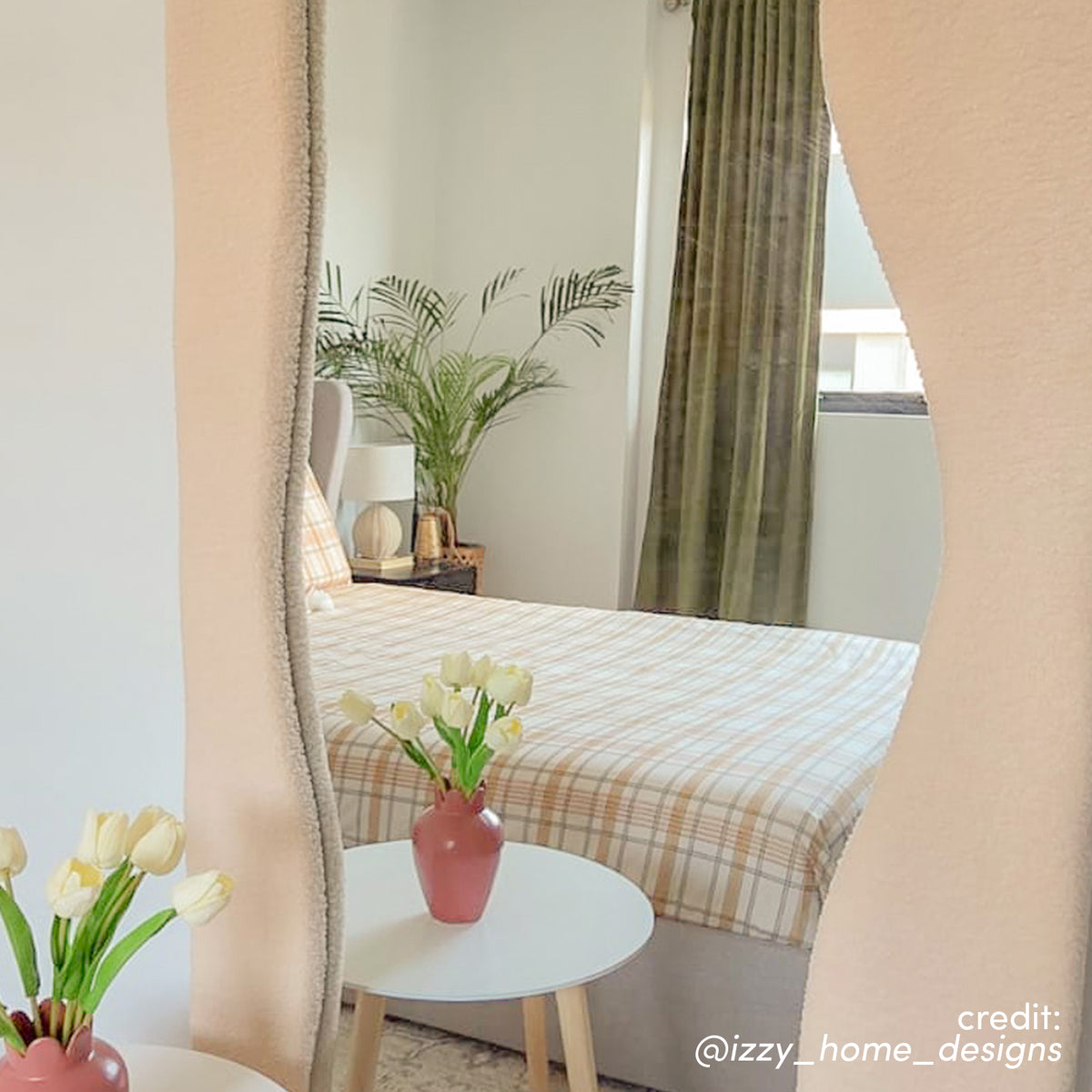 Sabrina 180cm Curved Full Length Mirror in Beige with wavy, textured frame reflecting a bedroom with bed, curtains, and side