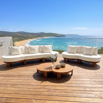Outdoor sofa set with coffee table on a terrace overlooking the ocean and beach.