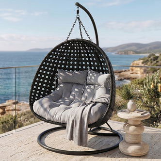 Buena 2-Seater Hanging Egg Chair in Black with grey cushions and throw, featuring a perforated rattan-style shell, chain