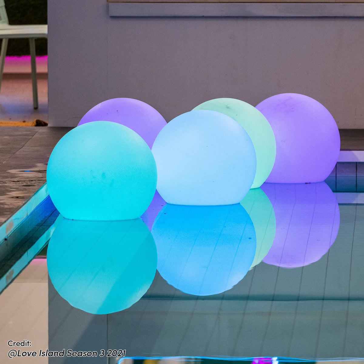 Sphero Floating LED Ball Bundles – Outdoor 60 & 40 cm, large glowing orbs elegantly arranged by a pool, reflecting pastel hues in the water, creating a luxurious outdoor ambiance.