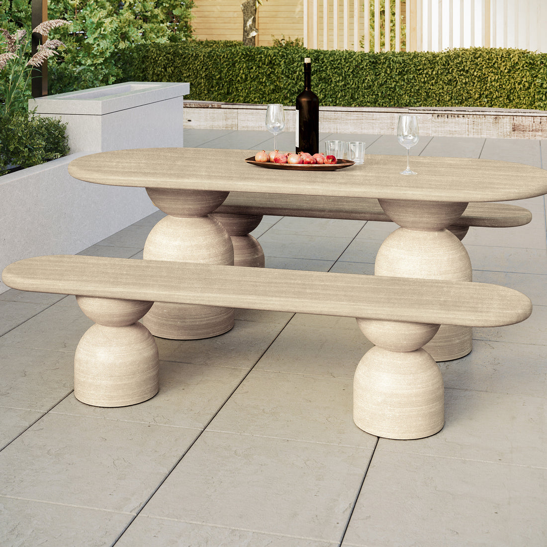 Lumen Indoor/Outdoor Concrete Dining Table Set with Bench Beige displayed in a stylish setting, showcasing its elegant oval shape and unique cone-shaped base on a coffee table adorned with a vase and wine glass.