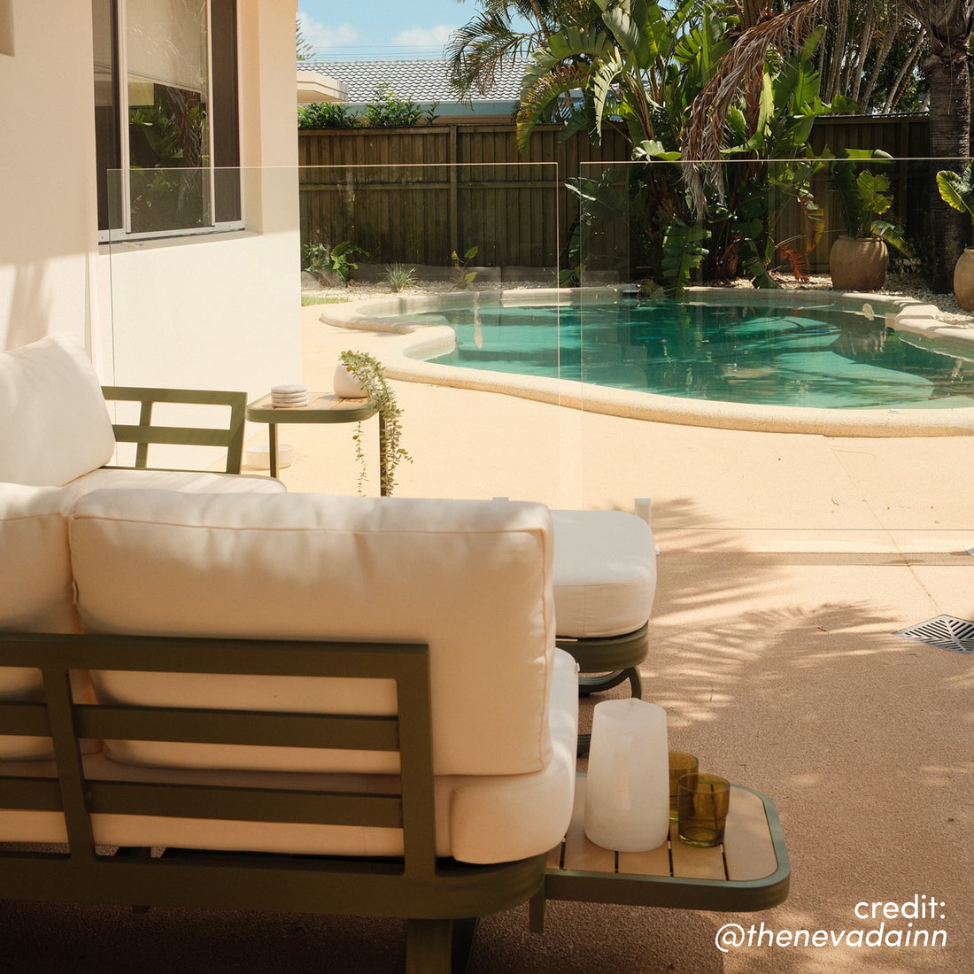 Paloma Modular Outdoor Lounge Set in Olive Green with cream cushions, side table and ottoman by a swimming pool
