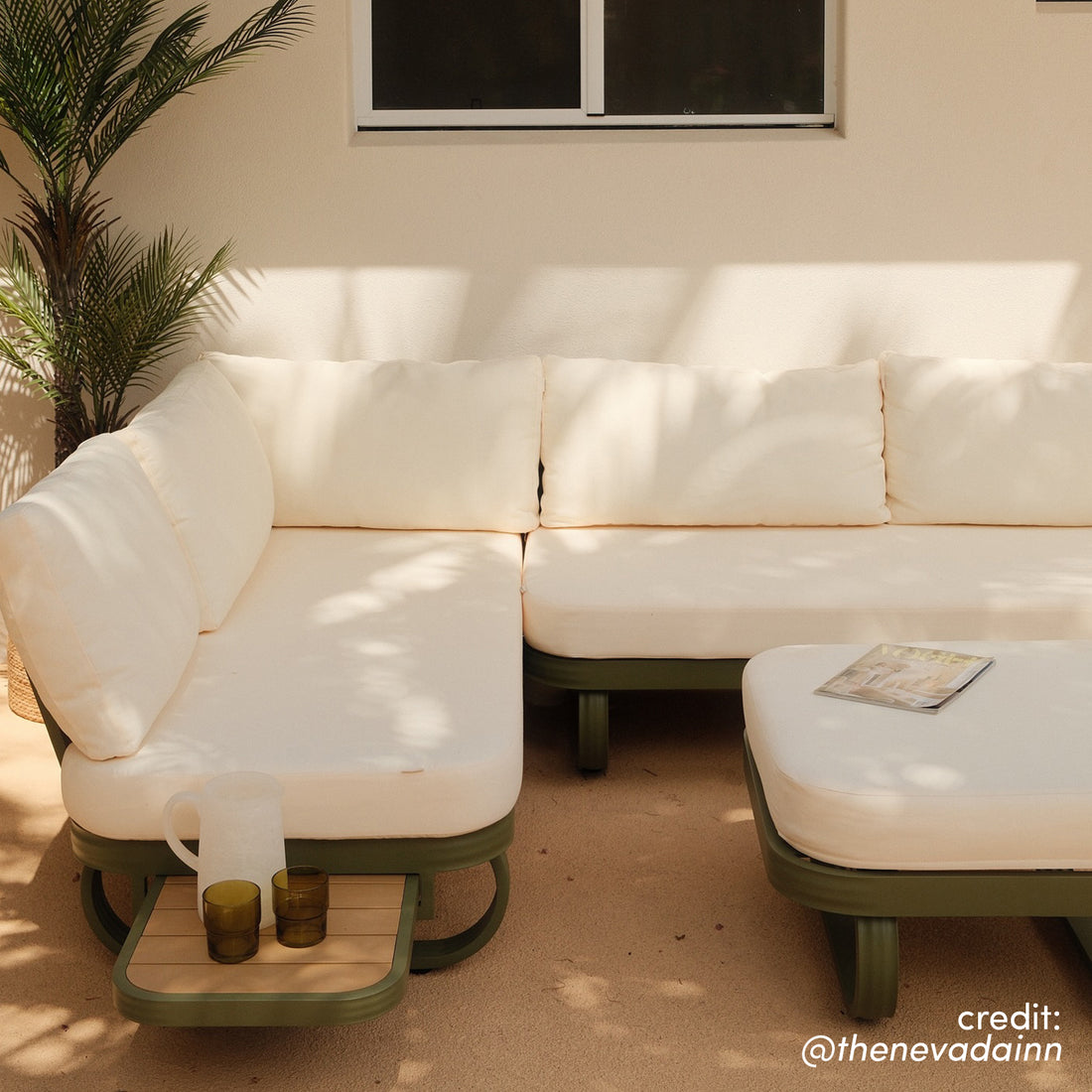 Paloma Modular Outdoor Lounge Set in Olive Green with cream cushions, side tray holding a pitcher and glasses, and matching