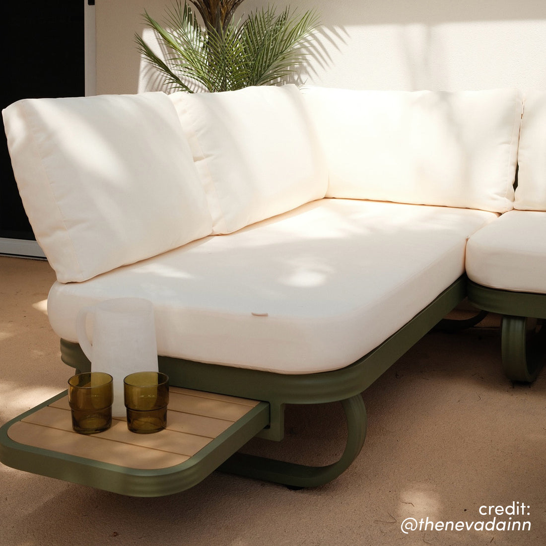Paloma Modular Outdoor Lounge Set in Olive Green with cream cushions and integrated wood-slatted side tray holding two amber