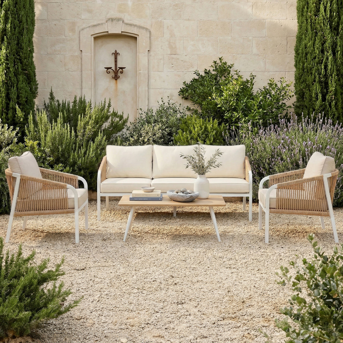 4-piece outdoor lounge set with white aluminum frames, tan woven rope sides, and cream cushions in a Mediterranean garden setting.